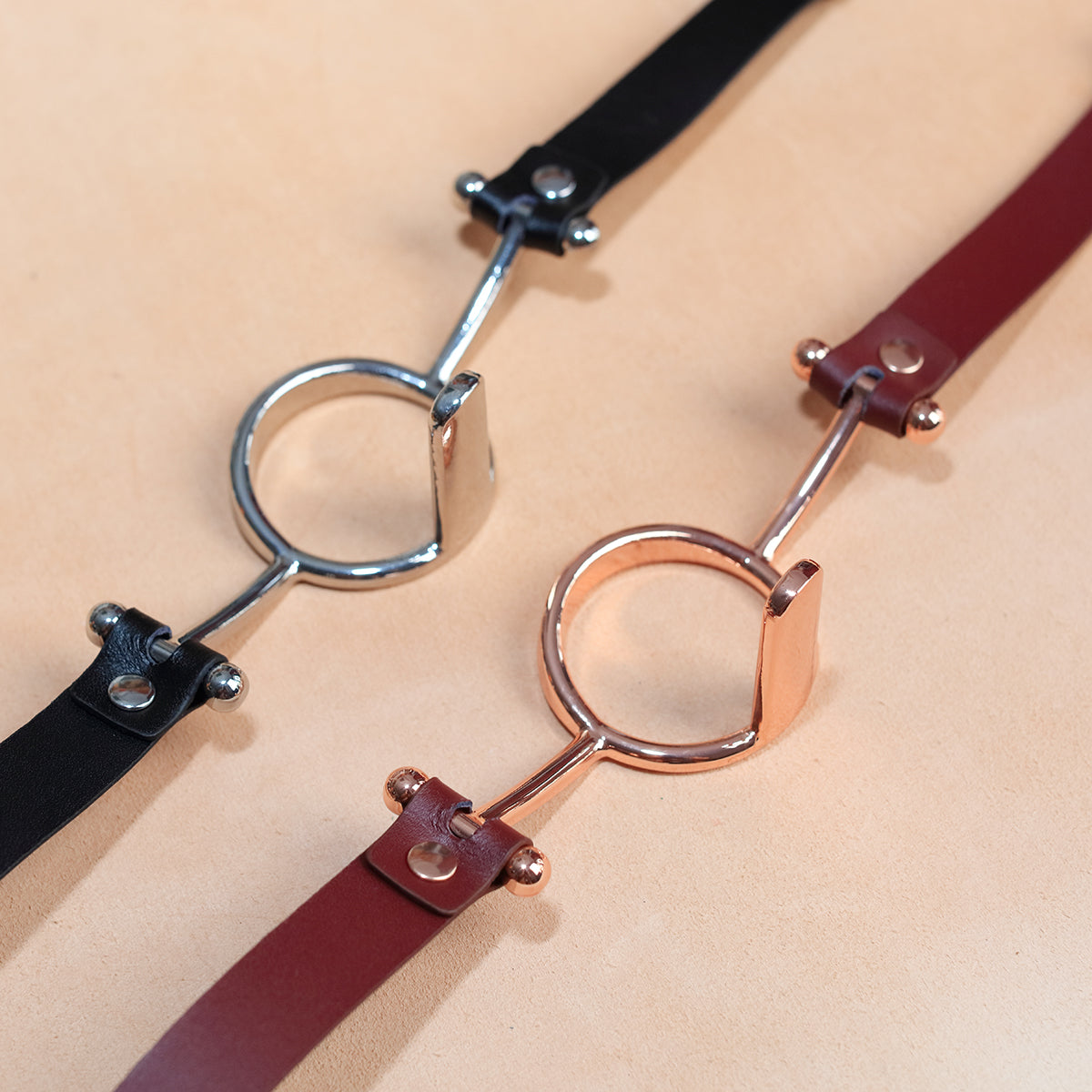 Close-up of luxurious gold metal O-ring tongue depressor gag with black premium vegan leather straps for oral bondage and deepthroat training by Sexy Maker.