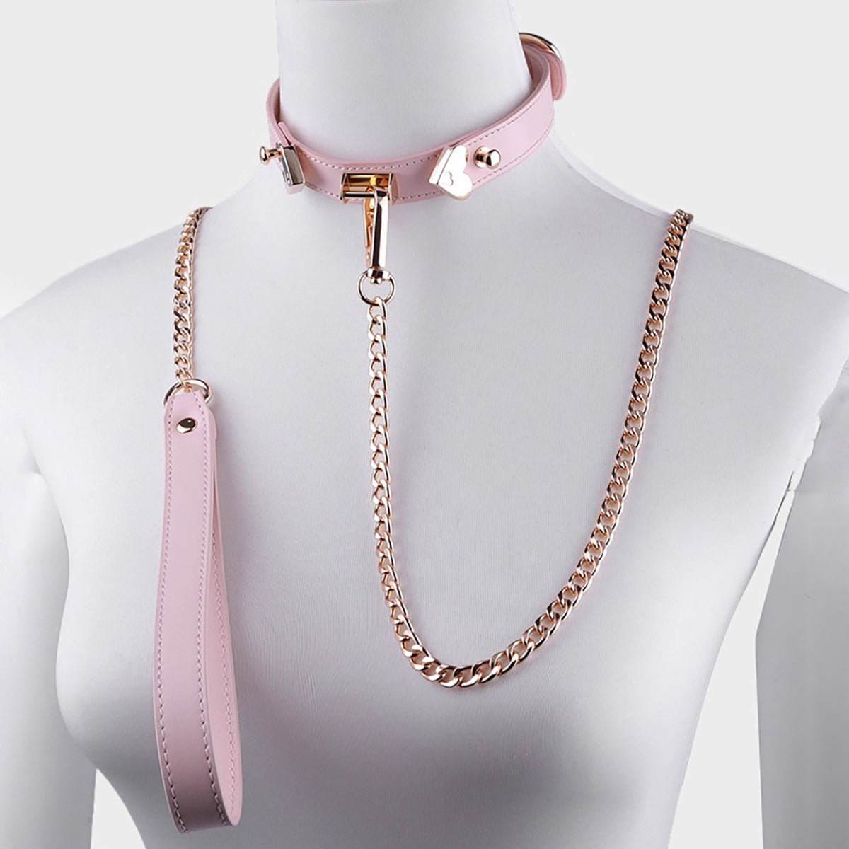 Close-up of gold heart-shaped hardware on light pink leather day collar