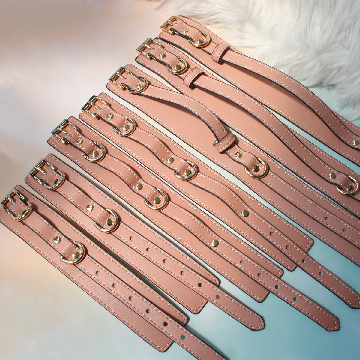 Close-up of gold-tone hardware on deep pink vegan leather wrist cuffs