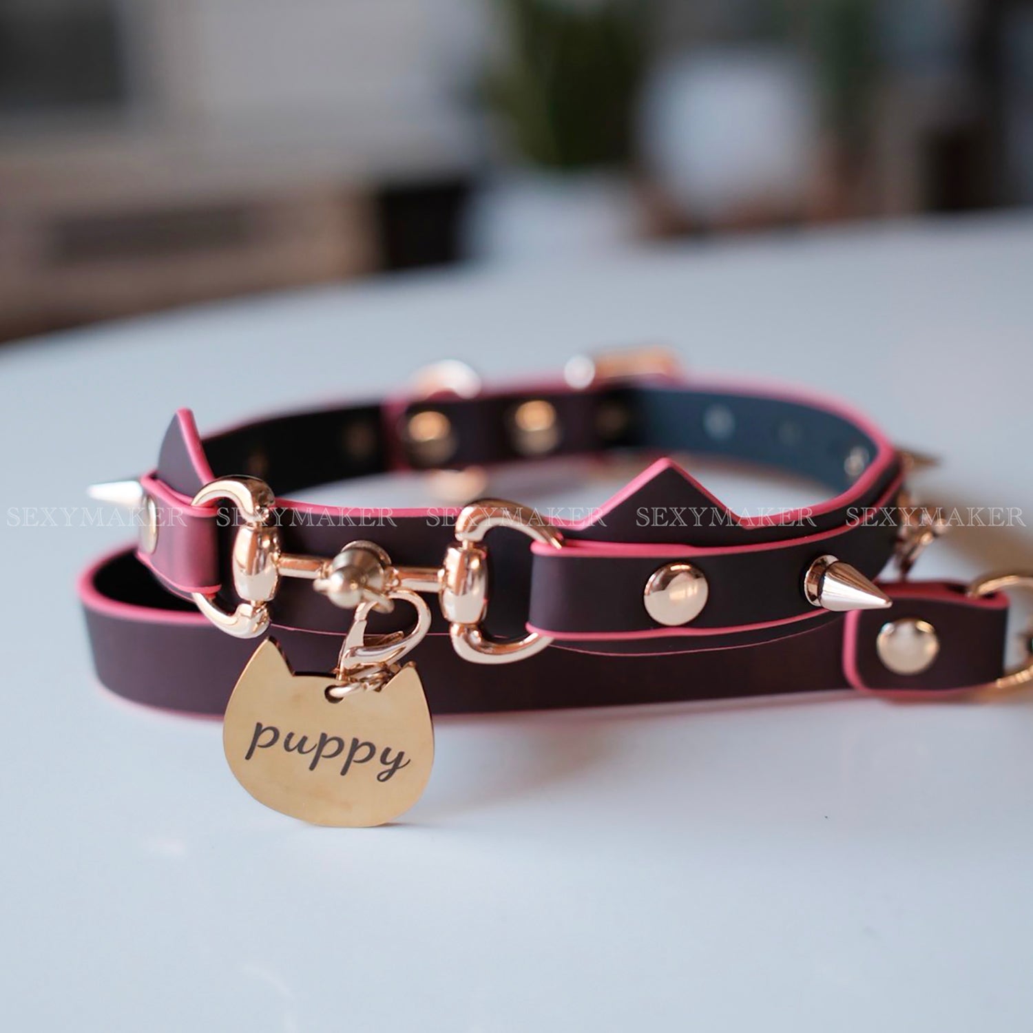 Close-up of heat-reactive color-changing black to red pet play collar featuring spiked cat ears and a gold puppy charm by Sexy Maker.