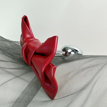 Front view of the Glossy Bow Anal Plug featuring a polished metal body and a black faux-leather ribbon, available on SexyMaker.
