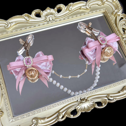 Close-up of adjustable pink ribbon nipple clamps with connecting chain and sparkling stones, beginner-friendly romantic BDSM jewelry by Sexy Maker.