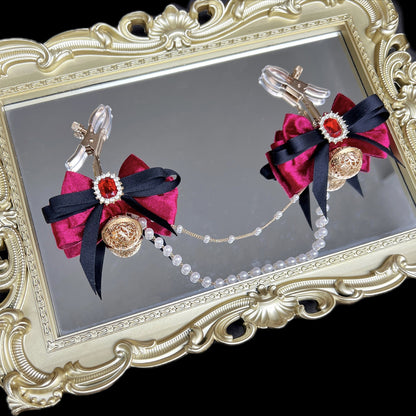 Close-up of adjustable wine red ribbon nipple clamps with connecting chain and sparkling stones, beginner-friendly romantic BDSM jewelry by Sexy Maker.