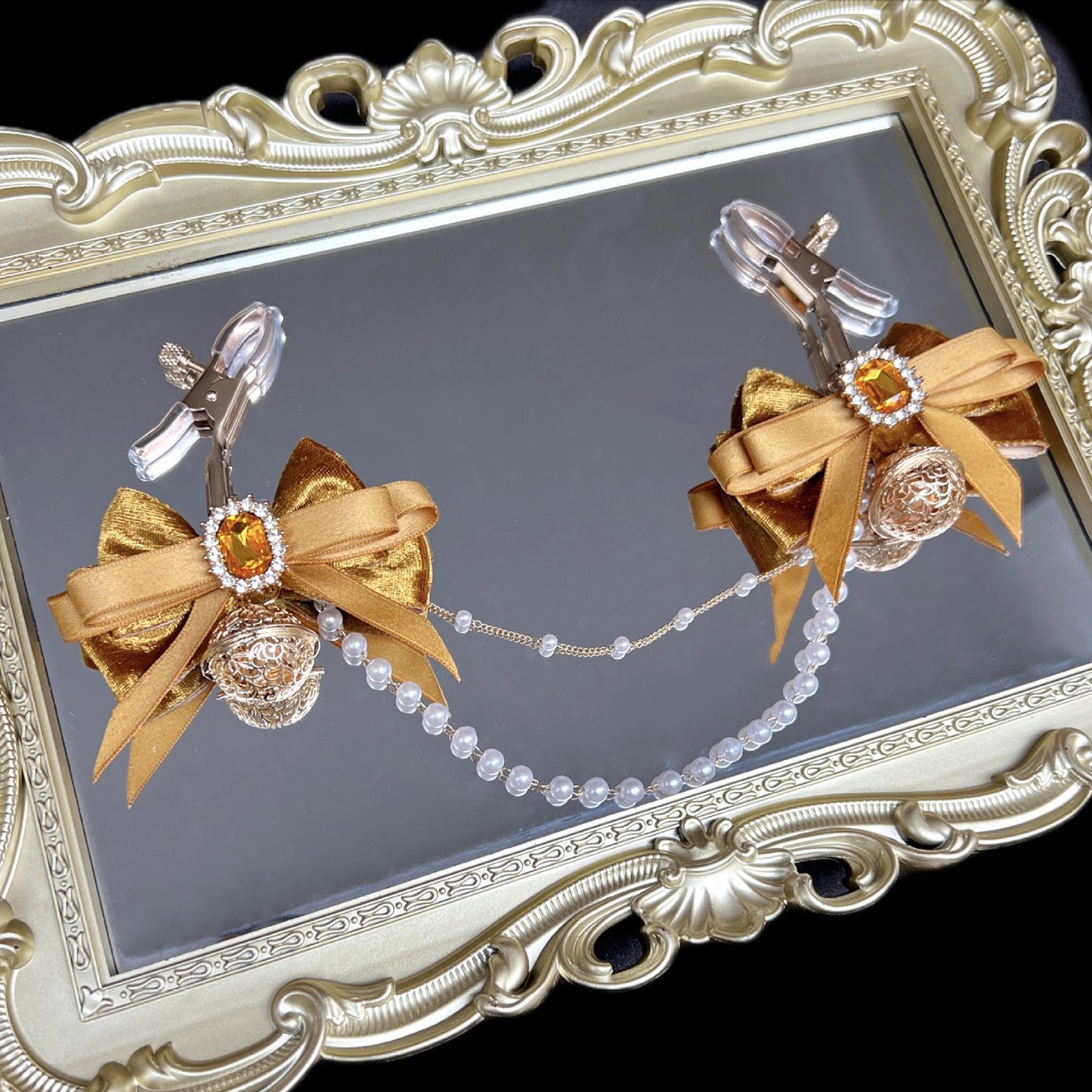Close-up of adjustable orange ribbon nipple clamps with connecting chain and sparkling stones, beginner-friendly romantic BDSM jewelry by Sexy Maker.